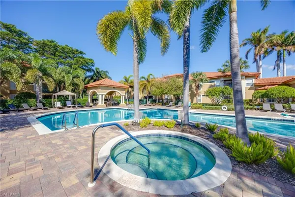a view of swimming pool with a lounge chair and palm trees