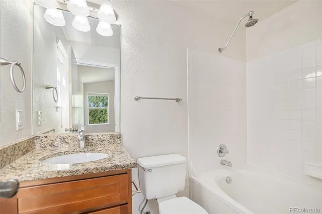 a bathroom with a granite countertop sink mirror vanity and toilet