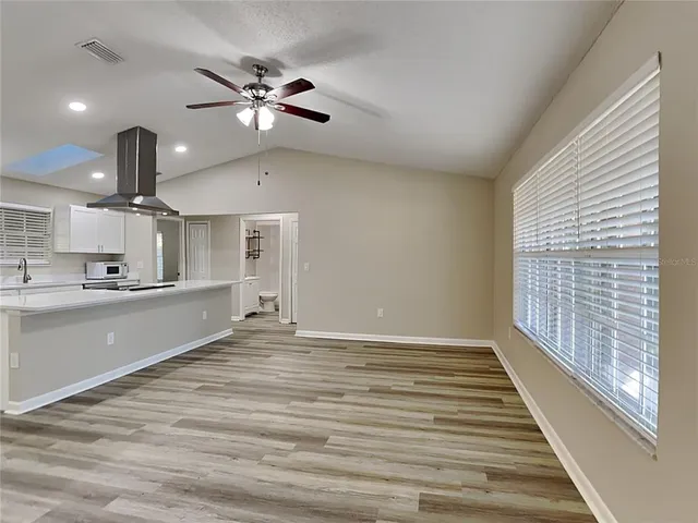 a view of an empty room with a window and wooden floor