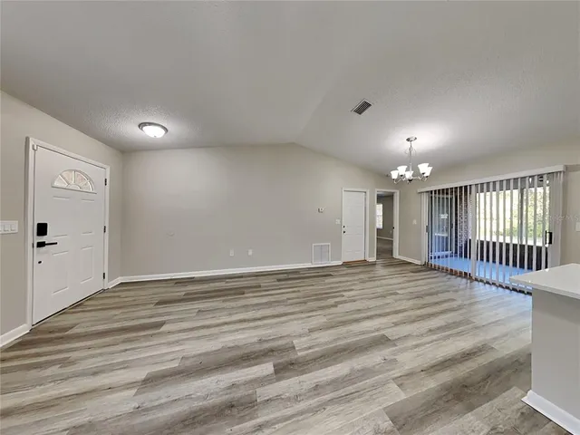 a view of an empty room with wooden floor and windows