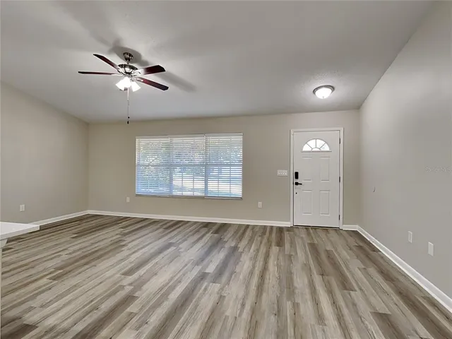 a view of empty room with wooden floor and fan