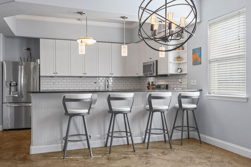 323 Main Street Destin, FL 32541 - Photo 25 of 43 a kitchen with stainless steel appliances granite countertop a table chairs a microwave and cabinets