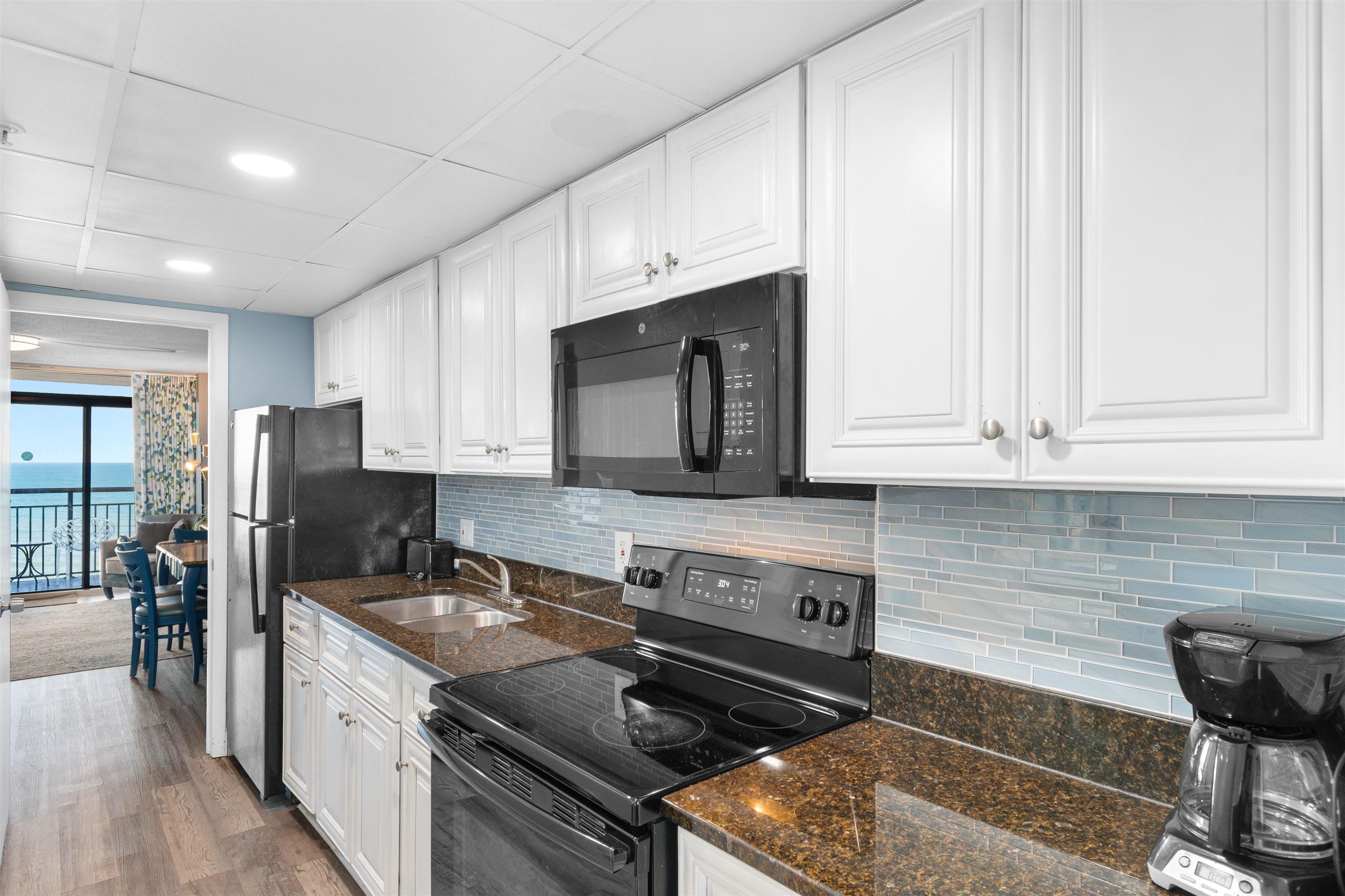 1501 South Ocean Boulevard, Unit 1237 Myrtle Beach, SC 29577 - Photo 11 of 40 Kitchen featuring black appliances, white cabinetry, decorative backsplash, dark stone countertops, and recessed lighting