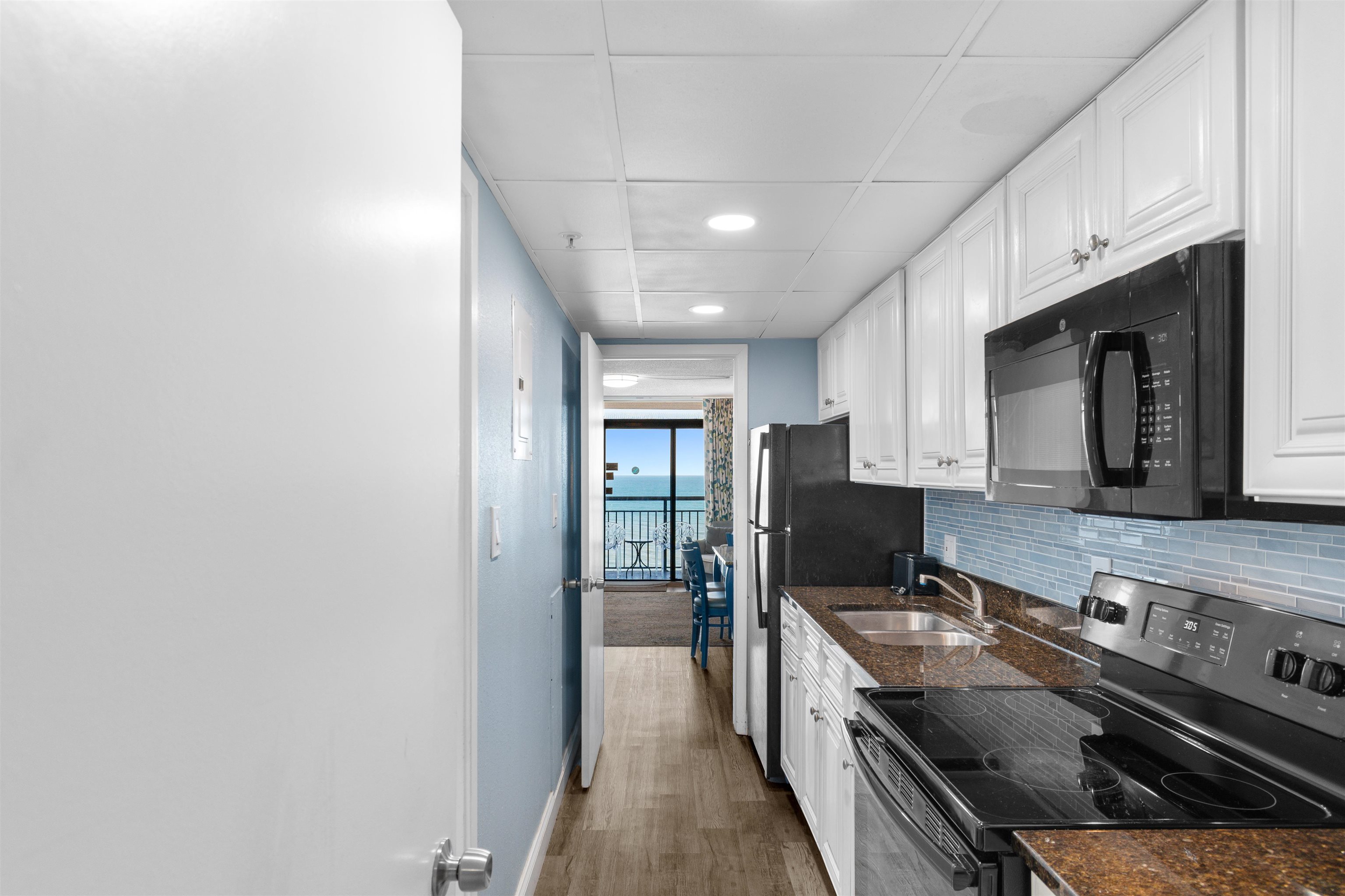 1501 South Ocean Boulevard, Unit 1237 Myrtle Beach, SC 29577 - Photo 12 of 40 Kitchen featuring electric range oven, white cabinets, black microwave, dark stone counters, and recessed lighting