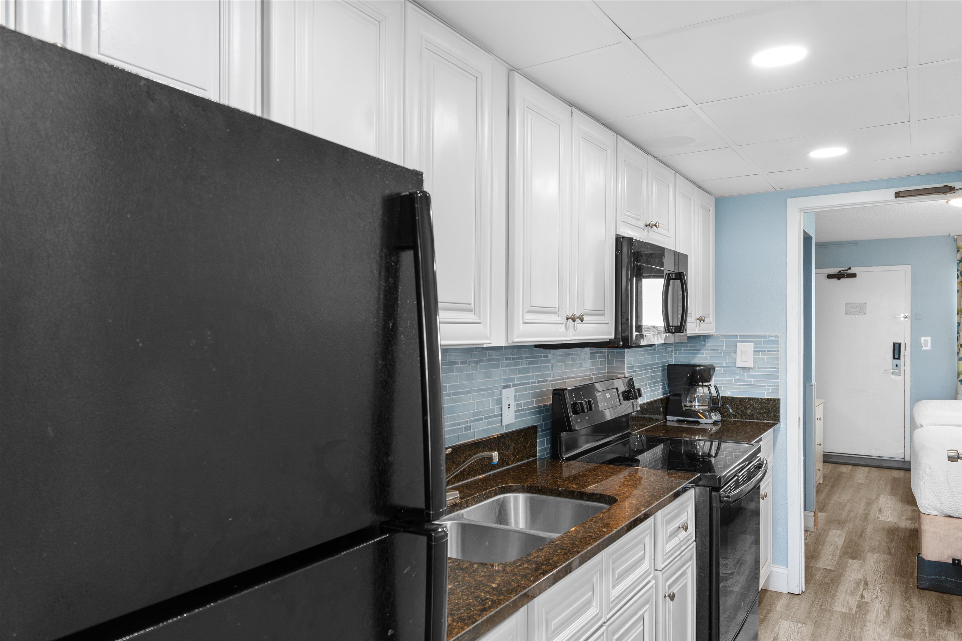 1501 South Ocean Boulevard, Unit 1237 Myrtle Beach, SC 29577 - Photo 13 of 40 Kitchen featuring black appliances, dark stone countertops, decorative backsplash, white cabinetry, and recessed lighting
