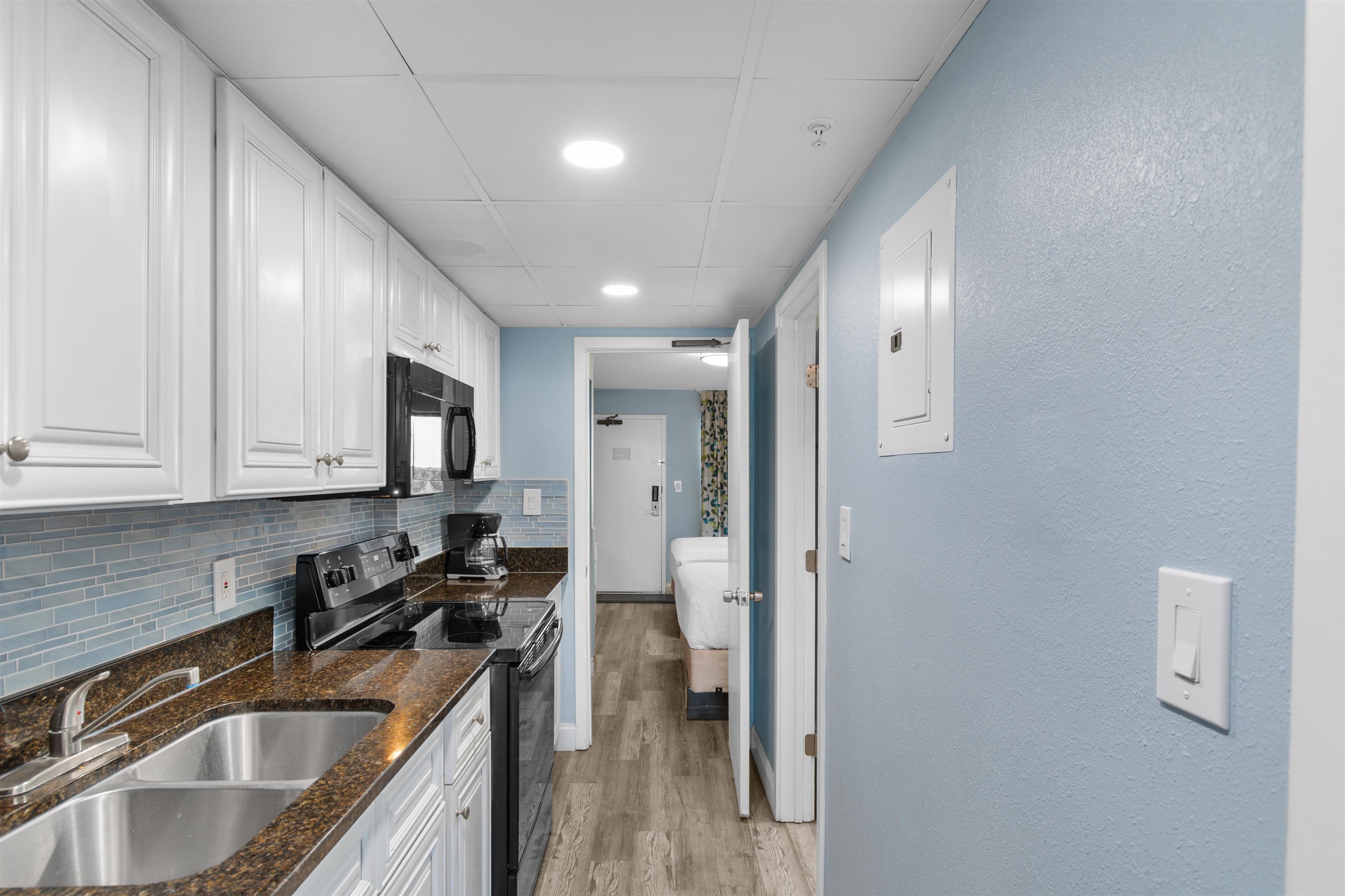 1501 South Ocean Boulevard, Unit 1237 Myrtle Beach, SC 29577 - Photo 14 of 40 Kitchen featuring black appliances, white cabinetry, dark stone counters, backsplash, and electric panel