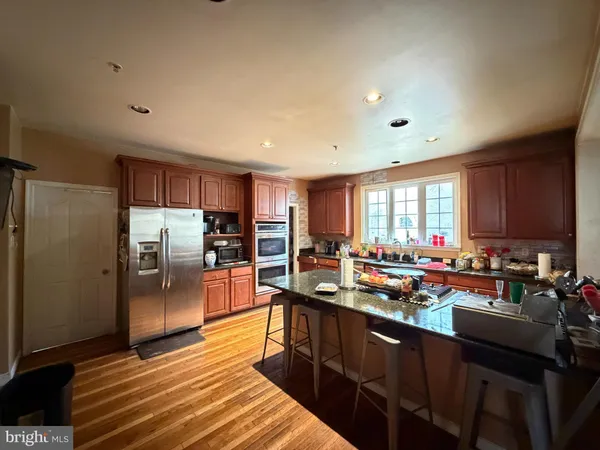 a kitchen with stainless steel appliances granite countertop a refrigerator a sink dishwasher a stove and white countertops with wooden floor