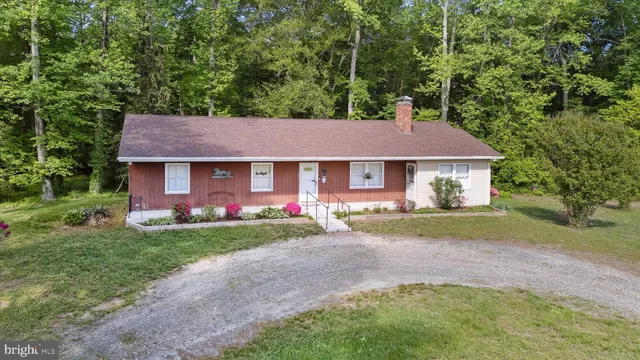 a front view of a house with a garden and trees
