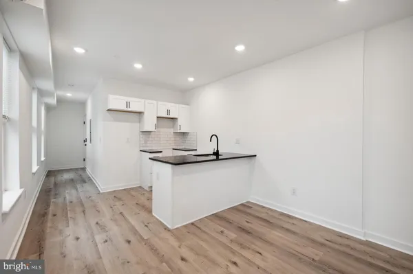 a kitchen with granite countertop a sink cabinets and wooden floor