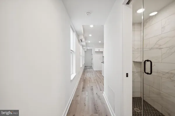 a view of a hallway with wooden floor and a bathroom