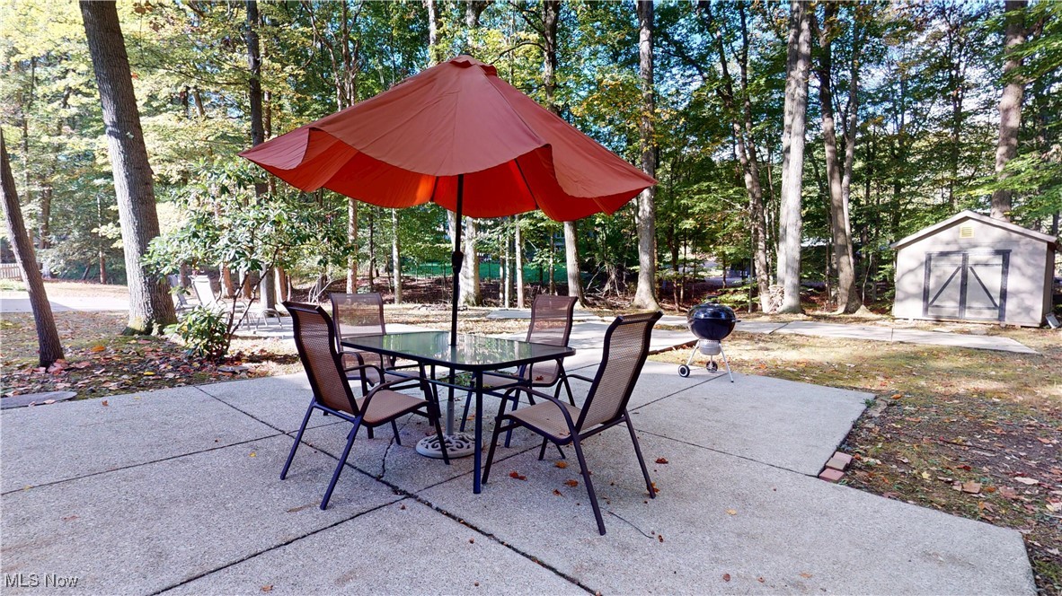 11650 River Moss Road Strongsville, OH 44136 - Photo 33 of 37 View of patio featuring view of wooded area, a storage unit, grilling area, and outdoor dining space