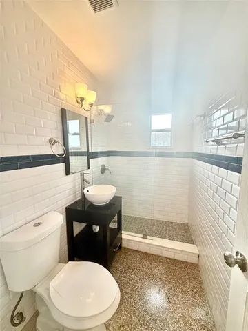 a bathroom with a sink a toilet a mirror and shower