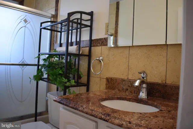 a bathroom with a granite countertop sink a mirror and shower