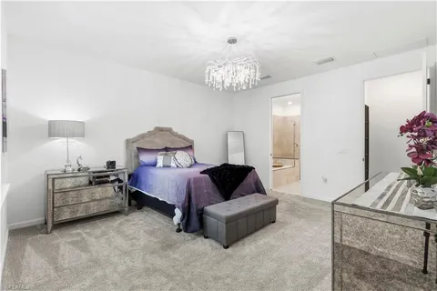 a spacious bedroom with a bed and a chandelier