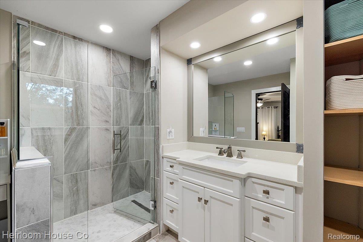 49001 Hanford Road Canton, MI 48187 - Photo 49 of 98 Glass-enclosed shower with large format tile surround, a white vanity with integrated sink, brushed nickel faucet, large wall mirror, and recessed lighting