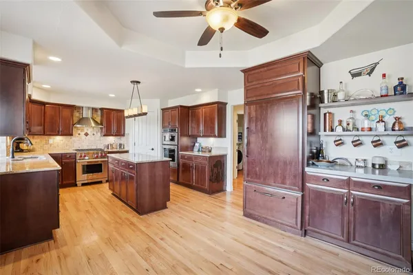 a kitchen with stainless steel appliances kitchen island granite countertop a refrigerator a stove top oven and cabinets