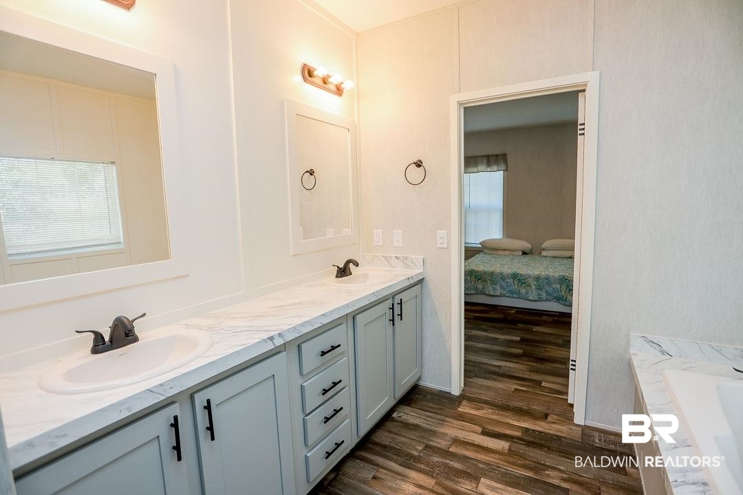 19180 Horseshoe Circle Seminole, AL 36574 - Photo 30 of 38 Bathroom featuring dark wood finished floors, double vanity, a tub, and connected bathroom