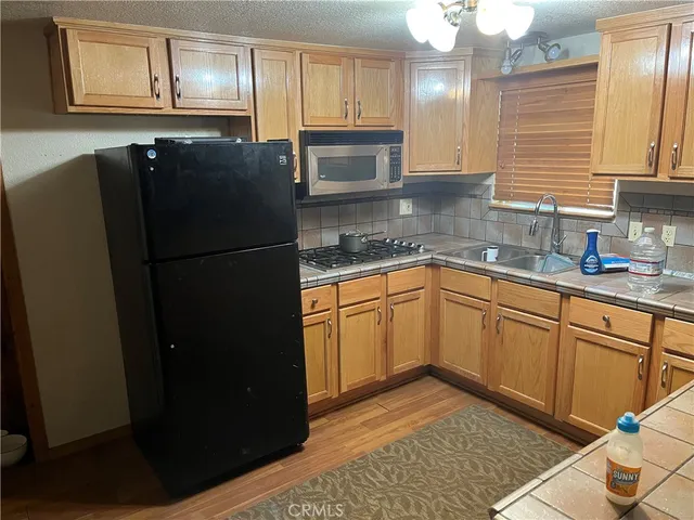 a kitchen with granite countertop stainless steel appliances a refrigerator a sink and cabinets