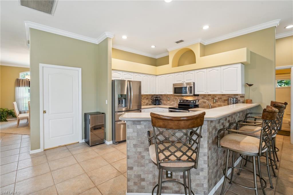 11446 Stratham Loop Estero, FL 33928 - Photo 8 of 27 a kitchen with refrigerator a stove and chairs