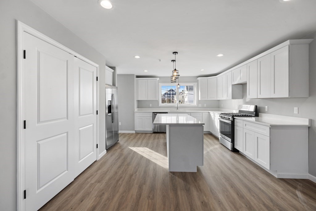 550 Spring Street, Unit 2 Fall River, MA 02721 - Photo 6 of 23 a kitchen with kitchen island white cabinets and stainless steel appliances