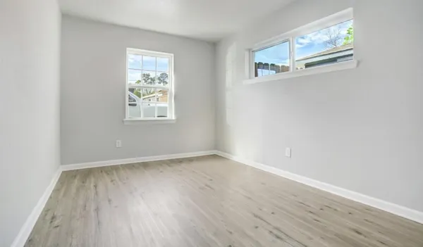 an empty room with wooden floor and windows