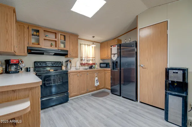 a kitchen with stainless steel appliances granite countertop a refrigerator a stove and a sink with wooden floor