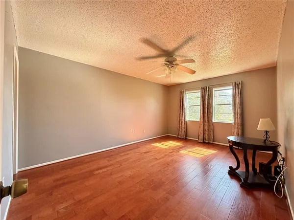 a view of an empty room with a window and wooden floor