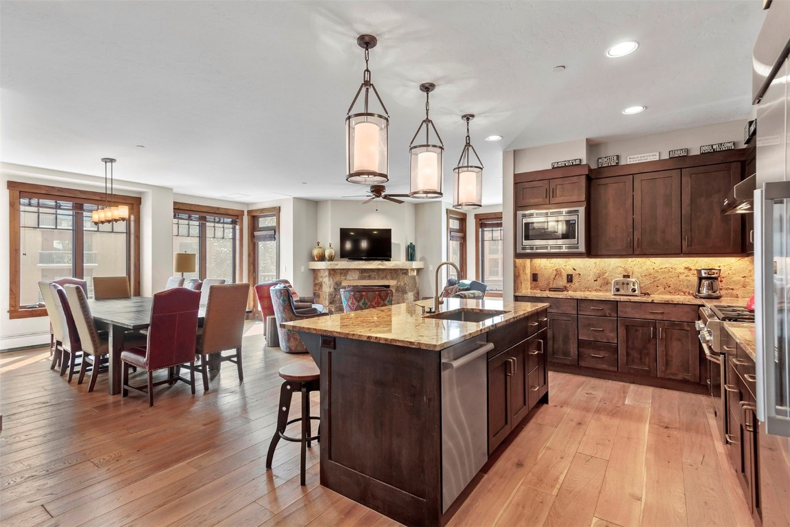 610 Columbine Road, Unit 6308 Breckenridge, CO 80424 - Photo 2 of 49 a kitchen with stainless steel appliances granite countertop wooden cabinets a sink dishwasher a stove and a dining table with wooden floor