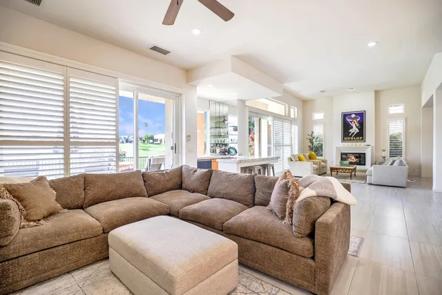 a living room with furniture kitchen view and a large window