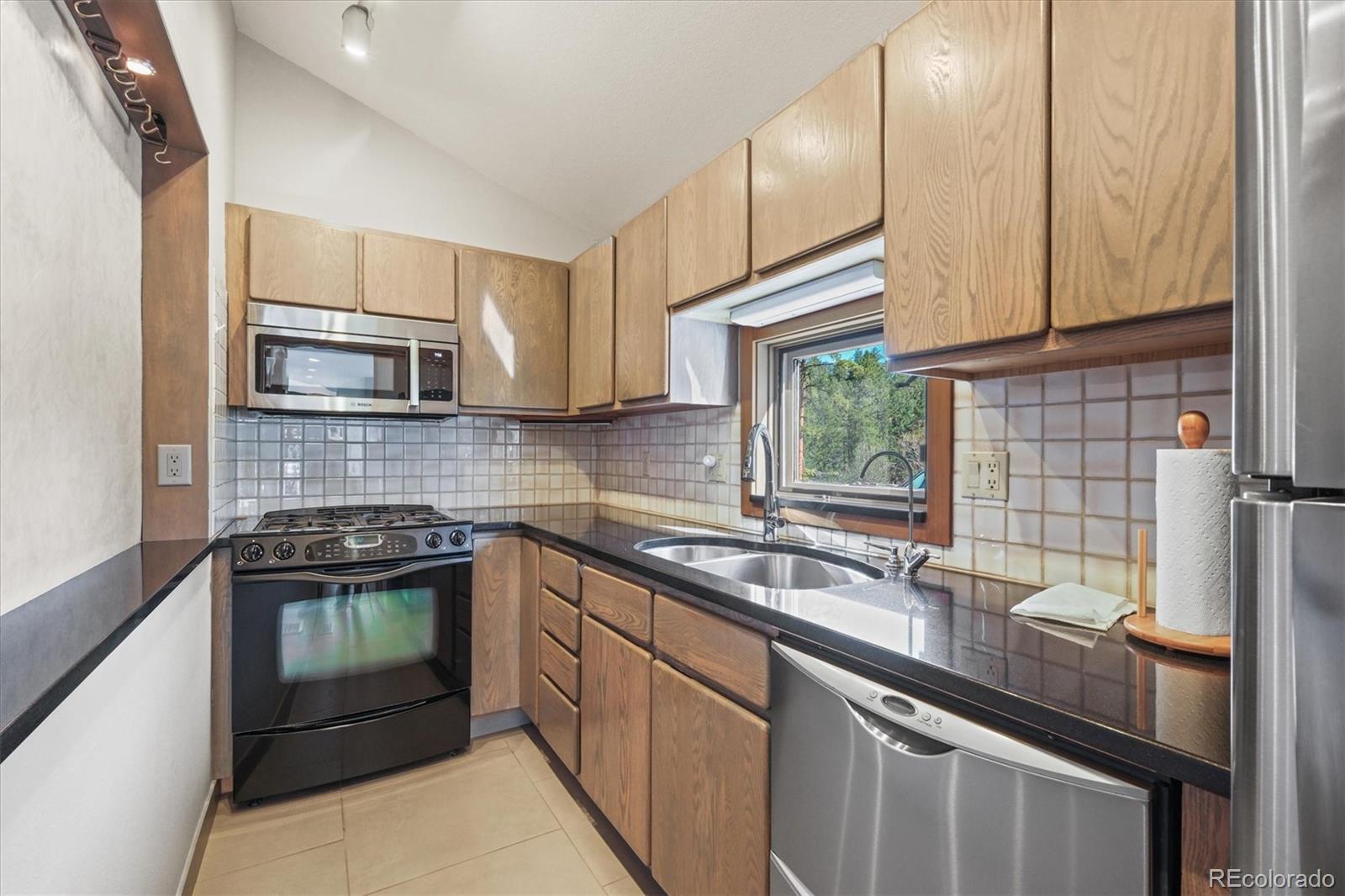 682 Buddy Road Bailey, CO 80421 - Photo 44 of 50 a kitchen with stainless steel appliances granite countertop a sink stove and microwave