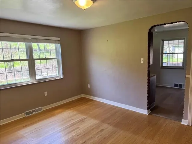 an empty room with windows fire place and a fireplace