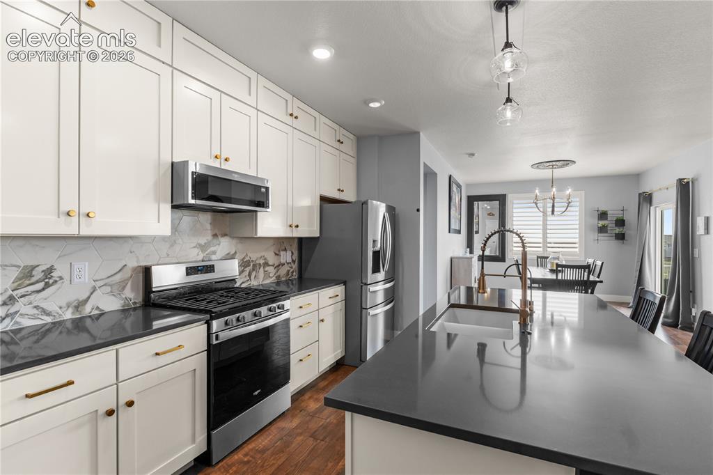 12781 Granite Ridge Drive Peyton, CO 80831 - Photo 13 of 41 Quartz countertops, a pantry, upgraded appliances and gas range, upgraded lighting fixtures. The cabinets have custom roll out storage shelves.