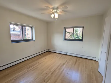 a view of empty room with wooden floor and fan