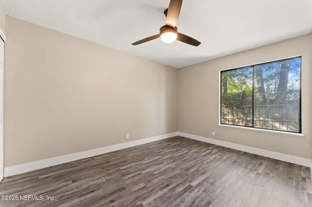 a view of an empty room with window and hardwood floor