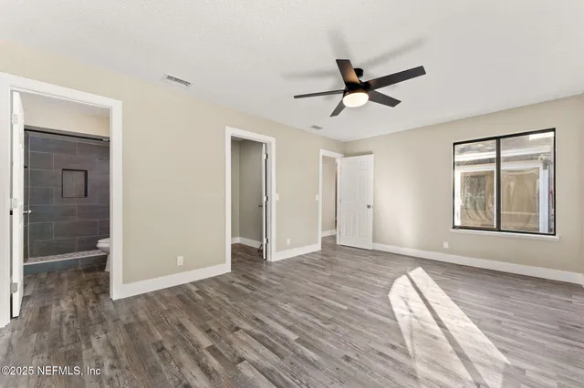 a view of empty room with wooden floor and fan