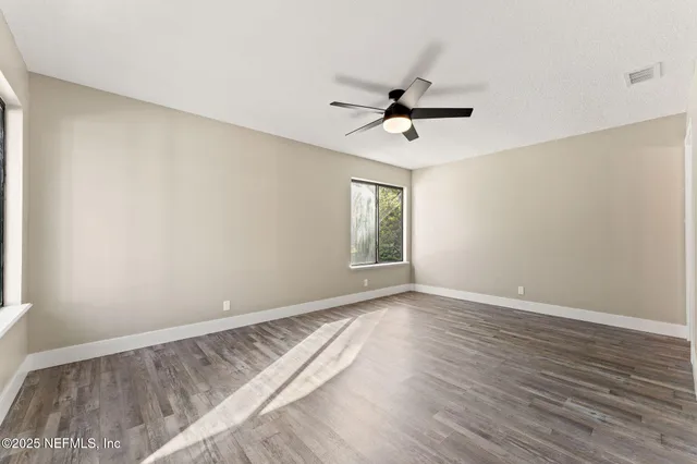 a view of empty room with wooden floor and fan