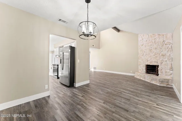 a view of a room with wooden floor fireplace and windows