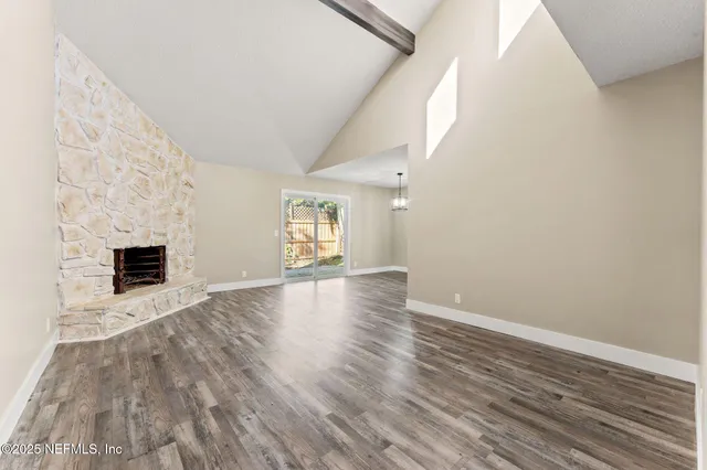 a view of empty room with wooden floor and fireplace