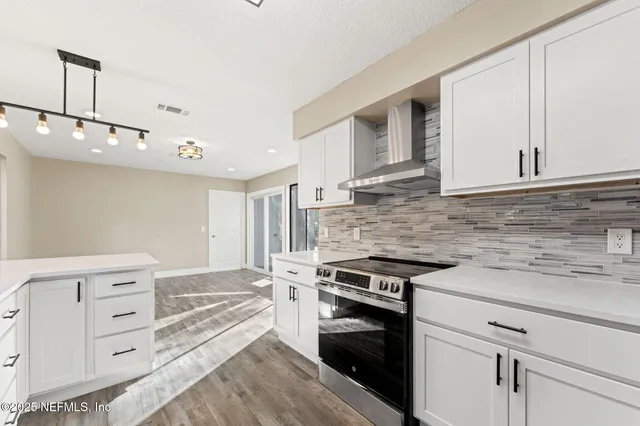 a kitchen with cabinets stainless steel appliances and wooden floor