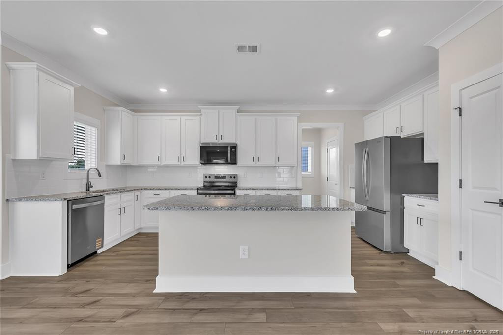 136 Camp Rock Road Lillington, NC 27546 - Photo 13 of 43 a large kitchen with stainless steel appliances granite countertop a stove a sink a refrigerator and white cabinets with wooden floor