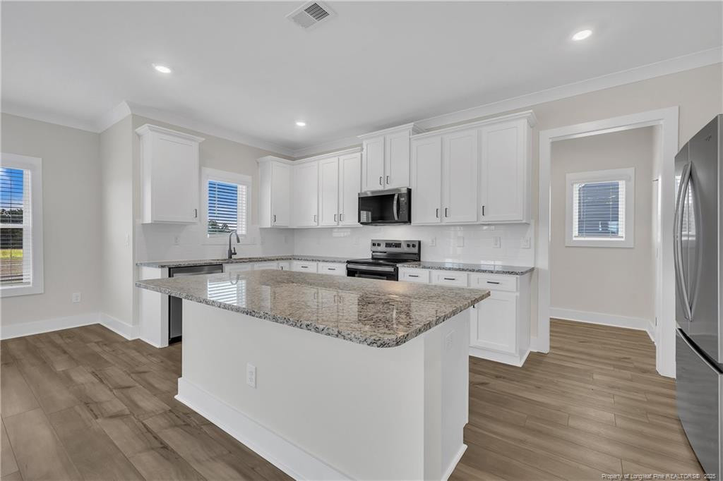 136 Camp Rock Road Lillington, NC 27546 - Photo 14 of 43 a kitchen with stainless steel appliances granite countertop a sink dishwasher a stove top oven a refrigerator with white cabinets and wooden floor