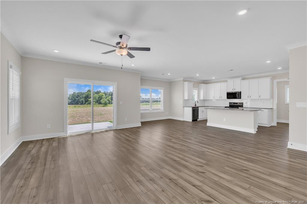 136 Camp Rock Road Lillington, NC 27546 - Photo 8 of 43 a view of an empty room with wooden floor and a kitchen