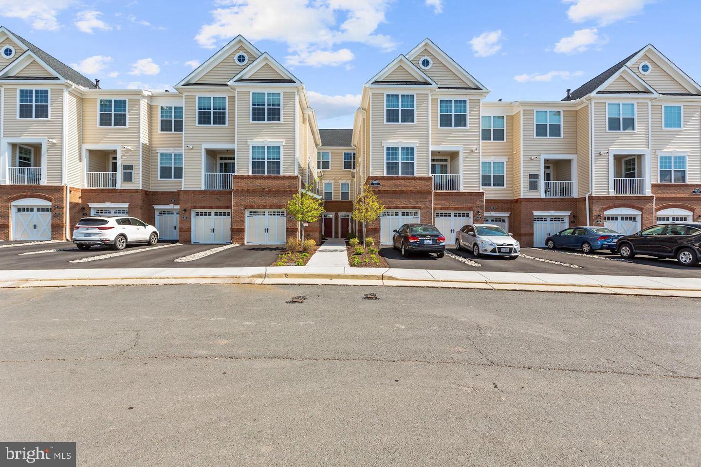 43032 Stuarts Glen Terrace, Unit 110 Ashburn, VA 20148 - Photo 1 of 1 a front view of a building with lot of cars and trees