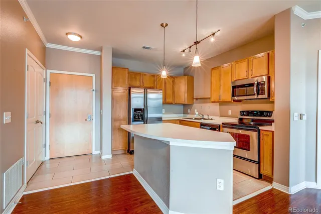 a kitchen with stainless steel appliances granite countertop a refrigerator a sink dishwasher a stove and white cabinets with wooden floor