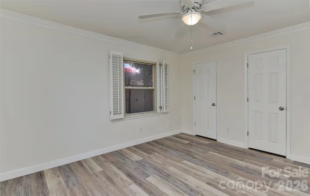 a view of empty room with wooden floor and fan
