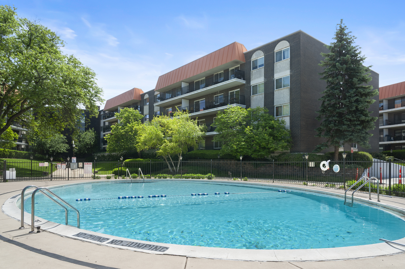 4949 Golf Road, Unit 101 Skokie, IL 60077 - Photo 21 of 22 a view of a swimming pool with a bench and trees around