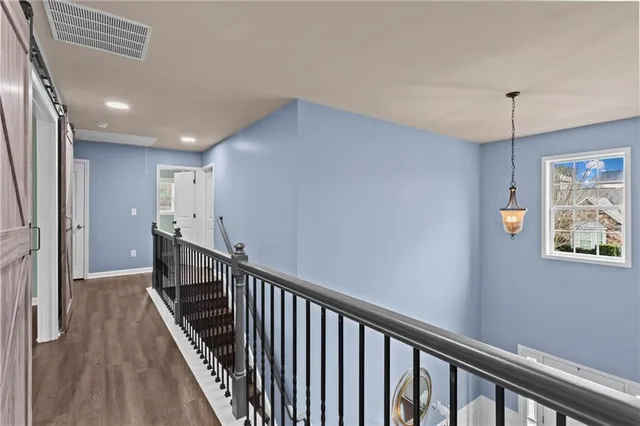 an empty room with wooden floor chandelier fan and windows