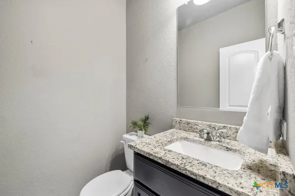 a bathroom with a granite countertop sink a mirror and a toilet
