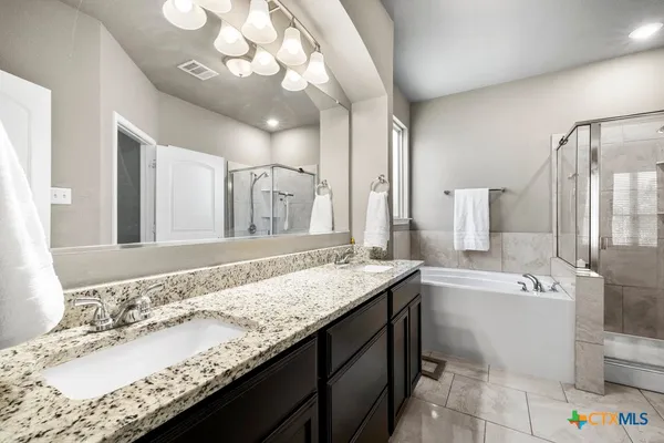 a bathroom with a granite countertop sink a large mirror and bathtub