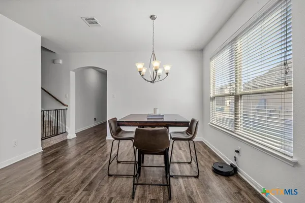 a dining room with wooden floor a chandelier a wooden table and chairs